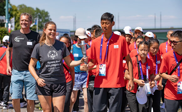 Chinesische und europäische Sportlerinnen mit der olympischen Fackel
