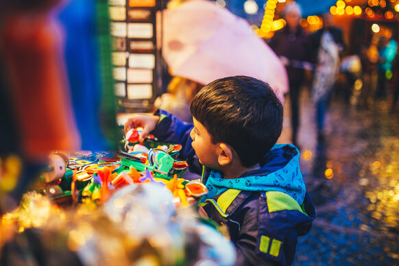 Ein kleiner Junge schaut sich Spielsachen auf dem Weihnachtsmarkt an.