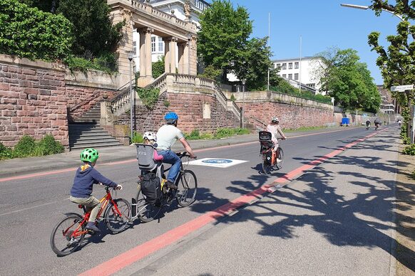 Das Bild zeigt zwei Erwachsene und zwei Kinder, die auf dem Fahrrad auf einer neuen Fahrradstraße am Rheinufer unterwegs sind.