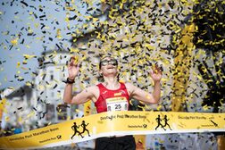 Die Siegerin des Halbmarathons durchläuft im Konfettiregen das Zielband