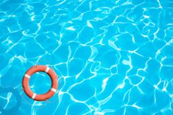 Ein Rettungsring schwimmt in der Ecke eines Schwimmbeckens mit sehr blauem Wasser