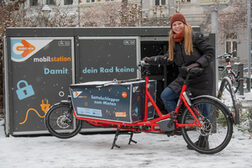 Das Bild zeigt eine Frau mit einem Lastenrad vor einer neuen Mobilstation in Bonn.