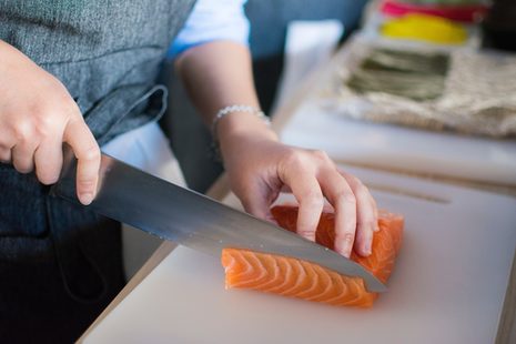 Ein Lachsfilet wird mit einem Messer geschnitten.