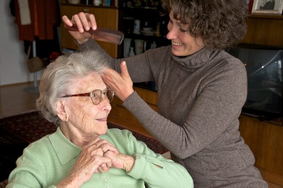 Pflegerin kämmt Seniorin die Haare