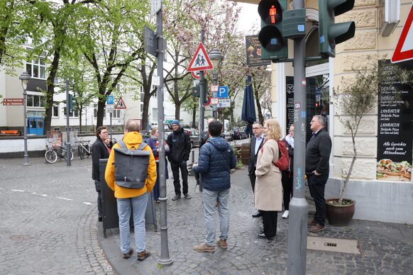 Rund zehn Menschen stehen in der Altstadt bei einem Rundgang an einer Ampel und sind im Gespräch.