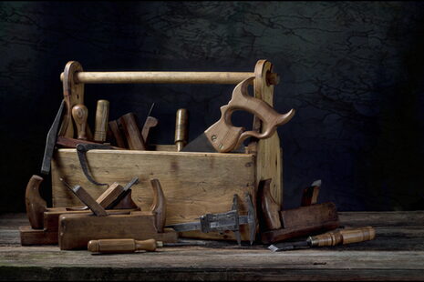 Eine hölzerne Werkzeugkiste und verschiedene Werkzeuge zur Holzbearbeitung wie Säge und Hobel