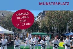 Das Plakat zeigt eine Gruppe Karatesportler auf dem Münsterplatz