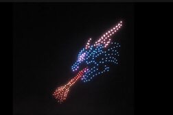 Drohnen "malen" einen feuerspeienden Drachen aus Licht an den Nachthimmel.