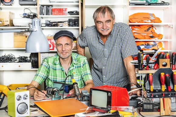 Zwei Männer in einer Werkstatt reparieren Dinge