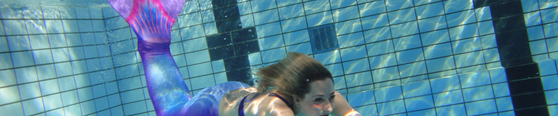 Aufnahme einer Frau, die mit einem Meerjungfrauenkostüm schwimmt