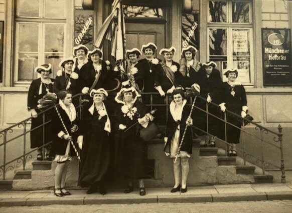 Die Gruppenaufnahme aus dem Jahr 1937 zeigt Frauen in schwarzer Bekleidung auf der Treppe eines Gasthauses