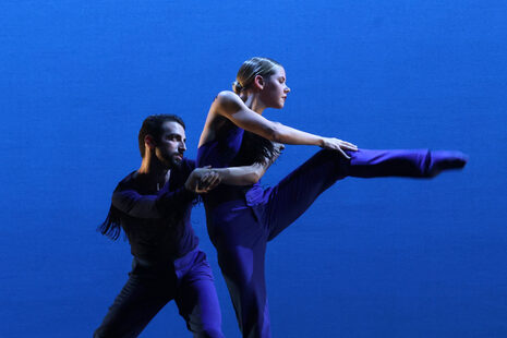 Ein Mann und eine Frau tanzen vor einem blauen Bühnenhintergrund