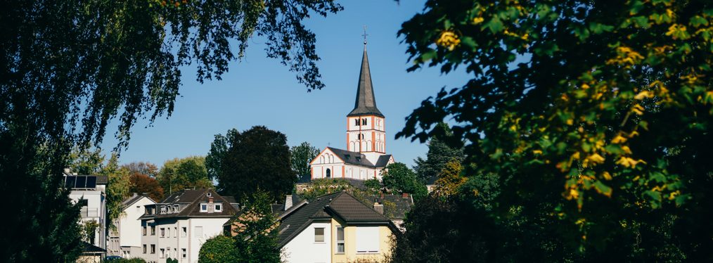Außenaufnahme der Doppelkirche Schwarzrheindorf von Bäumen umrahmt
