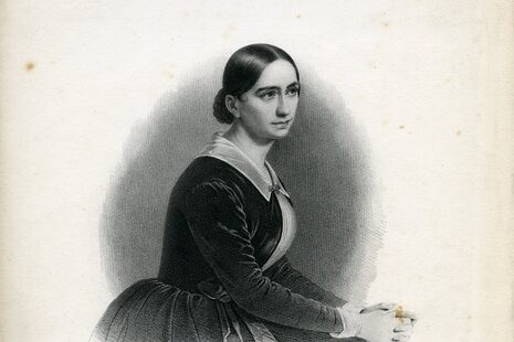 Zu sehen ist ein Porträtfoto in Schwarz-Weiß. Es zeigt eine Frau im Kleid, die zur Seite schaut. Es handelt sich um Clara Schumann.