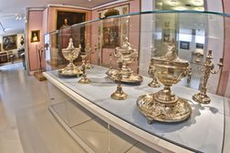 Silberne Dekorationsgegenstände und Kerzenleuchter in der Vitrine des Stadtmuseums