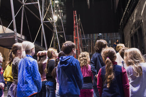 Eine Gruppe von Mädchen und Jungen besichtigt die Bühne der Oper Bonn