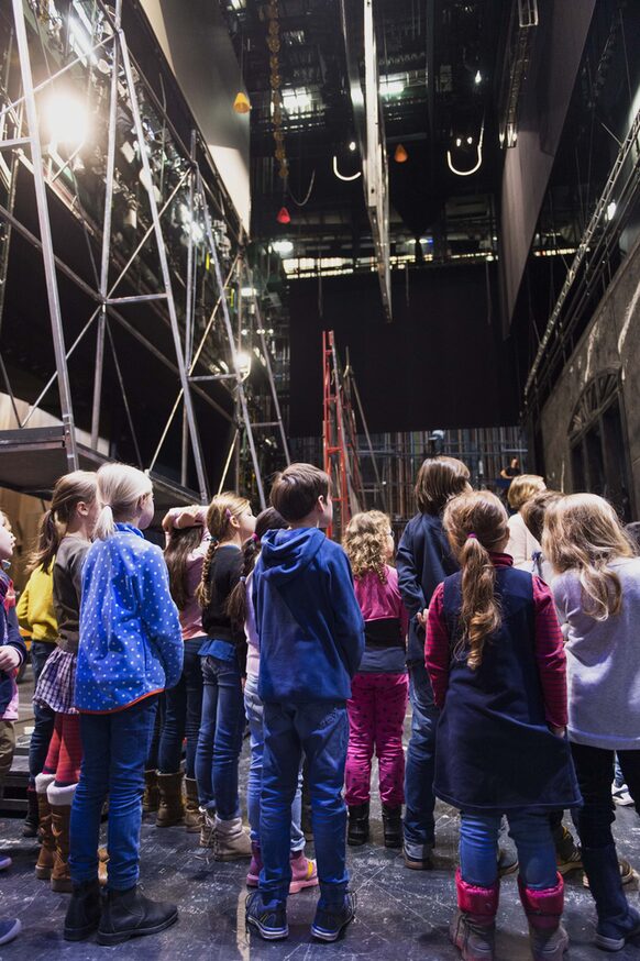 Eine Gruppe von Mädchen und Jungen besichtigt die Bühne der Oper Bonn