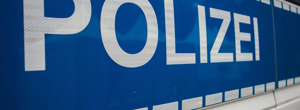 Nahaufnahme eines Polizeitransporters mit dem Schriftzug Polizei auf blauem Hintergrund