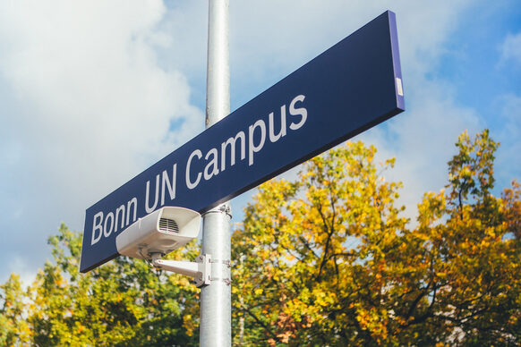 Blaues Hinweisschild der Bahnhaltestelle UN Campus