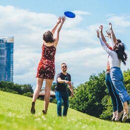 Vier junge Menschen spielen Frisbee in der Rheinaue.