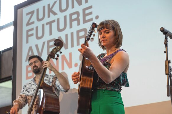 Das Bild zeigt eine Frau mit Gitarre und einen Kontrabassspieler.