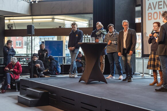 Das Bild zeigt eine Bühne, auf der Oberbürgermeisterin Katja Dörner spricht, umgeben von anderen Rednern.