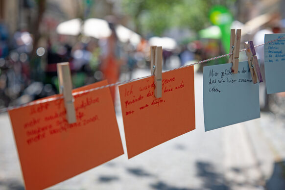 Das Foto zeigt kleine Zettel mit handschriftlich notierten Ideen, die an einer Schnur hängen.