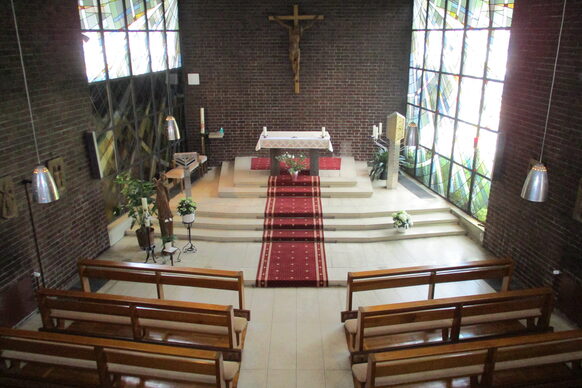Innenaufnahme einer Kapelle mit Altar, Jesus am Kreuz und Sitzbänken.