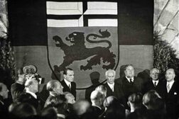 Thedor Heuss vor einer Fahne mit dem Bonner Stadtwappen