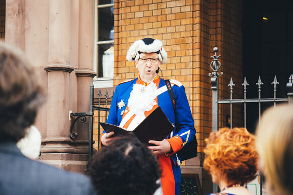Ein Gästeführer verkleidet als  "Leibgardist von Kurfürst Clemens August" vor einer Menschengruppe.