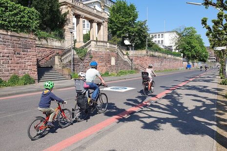 Eine Familie fährt auf Fahrrädern die Fahrradstraße am Rheinufer entlang.