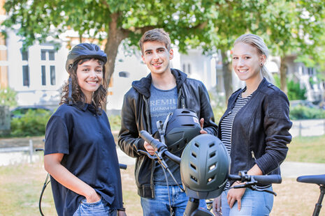 Drei junge Leute stehen an einem Fahrrad