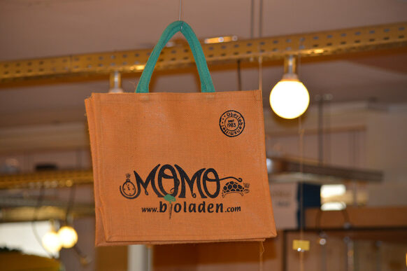 Orangefarbene Einkaufstüte mit Schriftzug Momo www.bioladen.com