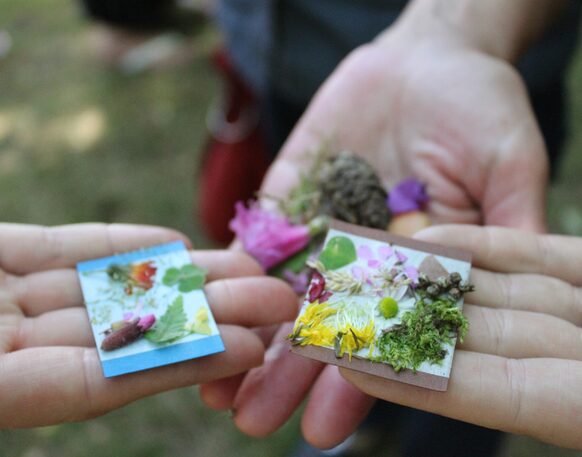 Auf drei Händen werden kleine Collagen mit Blättern, Moosen und Blüten präsentiert