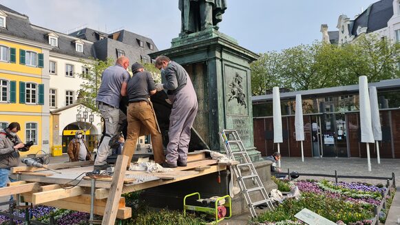 Drei Männer untersuchen das Beethoven-Denkmal auf dem Münsterplatz