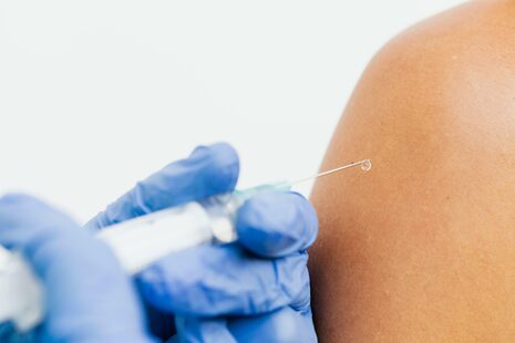 Eine Person bekommt eine Impfdosis in den Oberarm gespritzt