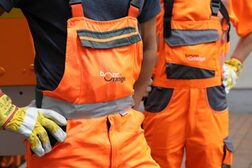 Zwei Mitarbeitende der bonnorange AöR in Arbeitskleidung mit den Hände mit Arbeitshandschuhen in den Hüften.