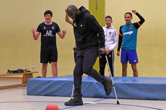 Hans Sarpei nimmt mit den Jugendlichen am aufgebauten "Selbsterfahrungsparcours" teil. Hier können die Teilnehmenden zum Beispiel erfahren und ausprobieren, wie es ist mit Krücken Fußball zu spielen.