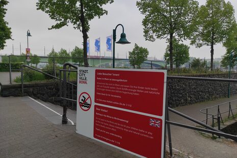 Warnschilder am Rhein weisen in Deutsch und Englisch auf die Gefahren von Baden im Rhein hin