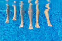 Unterwasseraufnahme von sechs Beinen, die im Wasser hängen