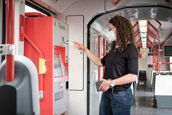 Eine Frau zahlt mit einem Zehn-Euro-Schein an einem Automaten in einer Stadtbahn