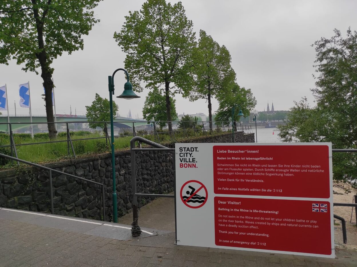 Eines der neuen Warnschilder entlang des Rheinufers. Auf die Gefahren wird nun auch auf Englisch hingewiesen.