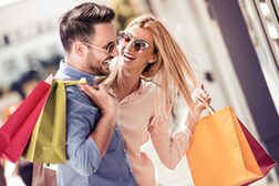 Ein Mann und eine Frau lachen sich beim Shoppen fröhlich an