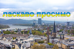 Luftaufnahme von Bonn mit Rhein und Siebengebirge mit Schriftzug "Willkommen" auf Ukranisch