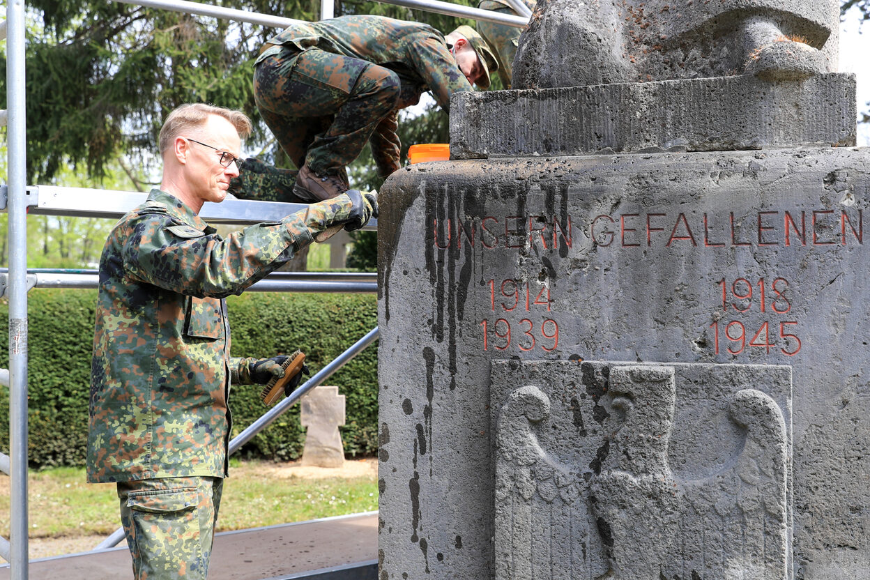 Zwei Soldaten reinigen einen Gedenkstein.