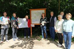 Vertreterinnen und Vertreter der Stadt Bonn, des Naturpark Rheinland und des Eifelvereins mit einer Karte an der Wandertafel an der Waldau.