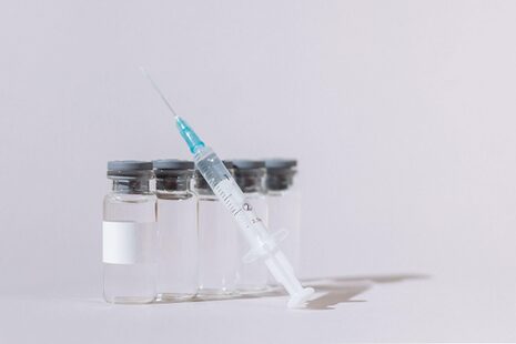 Fünf Fläschchen mit Impfstoff und eine Spritze