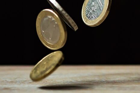 Euro Münzen fallen auf einen "Boden"/Tisch.