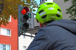 Ein Radfahrer schaut an einer Kreuzung auf einen Grünpfeil für Radverkehr.