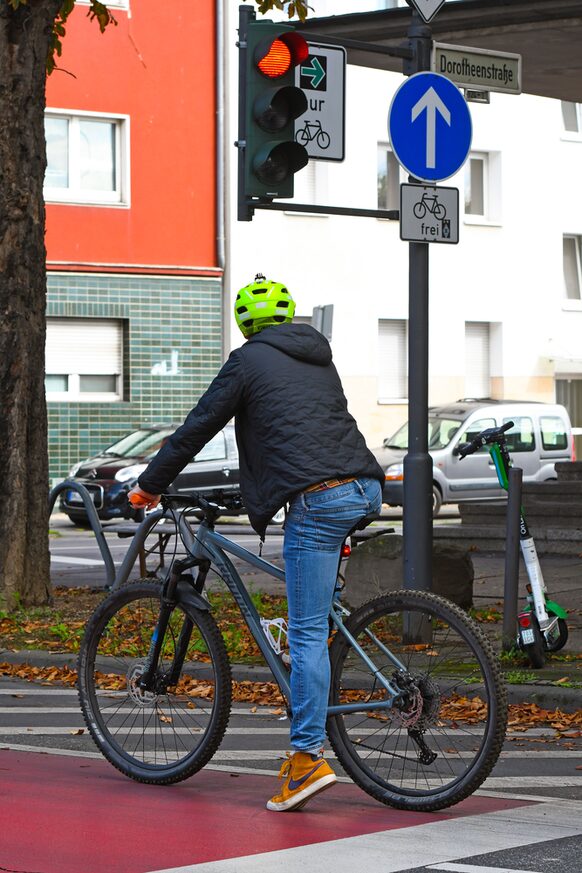 Ein Radfahrer stoppt kurz an einer Kreuzung mit Grünpfeil für Radverkehr.